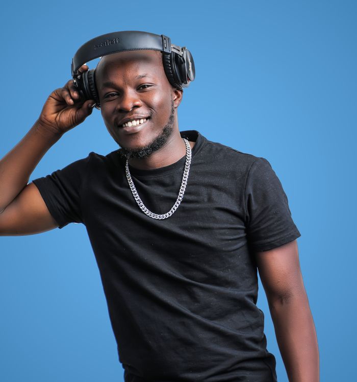 A cheerful man wearing headphones and a black shirt against a blue backdrop.